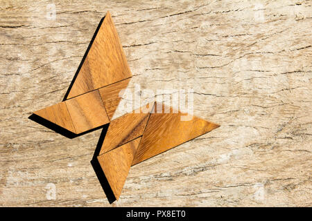 Hölzerne Tangram puzzle in fliegender Schmetterling Form Hintergrund Stockfoto