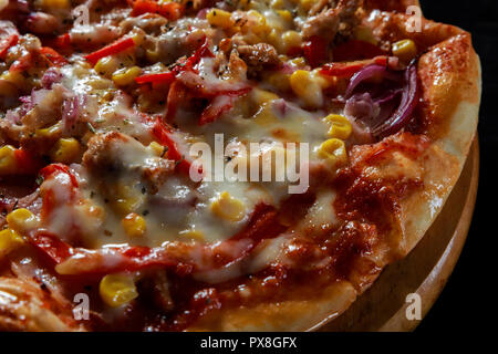 Pizza mit Mais, Speck, Paprika, Zwiebel, Parmesan und Huhn Stockfoto