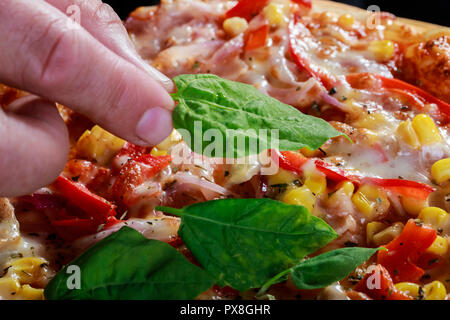 Pizza mit Hähnchen und Gemüse mit Mais, Speck, Paprika, Zwiebeln und Basilikum und Rucola Stockfoto