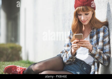 In der Nähe eines modernen hipster Frau mit roten, das über eine Anwendung in Ihrem Smartphone gerät Haar Stockfoto