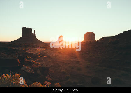 Klassische Ansicht des malerischen Monument Valley mit dem berühmten Fäustlinge und Merrick Butte im schönen goldenen Morgenlicht bei Sonnenaufgang im Sommer mit retro vin Stockfoto