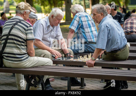 RIGA, Lettland - 18 Juli, 2018: Männer, die auf Parkbänken sitzen und spielen Schach. Stockfoto