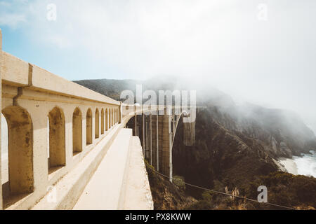 Panoramablick auf das historische Bixby Creek Bridge entlang der berühmten Highway 1 an einem sonnigen Tag mit Nebel im Sommer, Monterey County, Kalifornien, USA Stockfoto