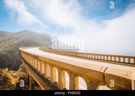 Panoramablick auf das historische Bixby Creek Bridge entlang der berühmten Highway 1 an einem sonnigen Tag mit Nebel im Sommer, Monterey County, Kalifornien, USA Stockfoto