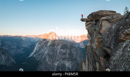 Eine furchtlose Wanderer steht auf einem überhängenden Felsen genießen den Blick auf die berühmten Half Dome am Glacier Point in schönen Abend dämmerung Blicken Stockfoto