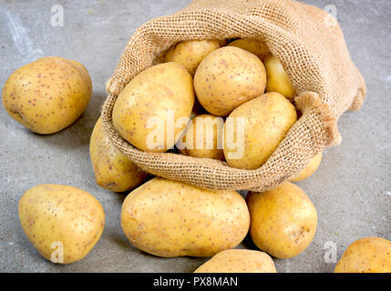 Frische rohe Kartoffeln in einem sackleinen Sack. Erdige Kartoffel Szene mit Sack, Anordnung auf einer hölzernen Hintergrund, kochen Zutat. Das gesunde Essen. Stockfoto