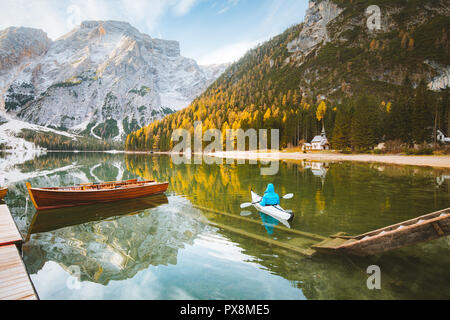 Schöne Aussicht von berühmten Lago di Braies mit traditonellen Ruderboot und junger Mann in Kajak bei Sonnenaufgang im Herbst, Dolomiten, Italien Stockfoto