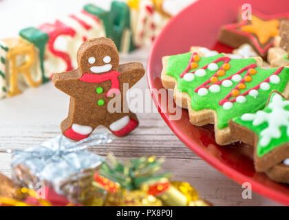 Lecker und süß gebackenen Weihnachtsplätzchen (Lebkuchen) mit schönen Weihnachten Dekoration in Rot Platte auf Licht Holztisch, Hintergrund, Nahaufnahme, Kopieren spac Stockfoto
