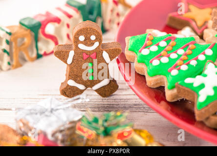 Lecker und süß gebackenen Weihnachtsplätzchen (Lebkuchen) mit schönen Weihnachten Dekoration in Rot Platte auf Licht Holztisch, Hintergrund, Nahaufnahme, Kopieren spac Stockfoto