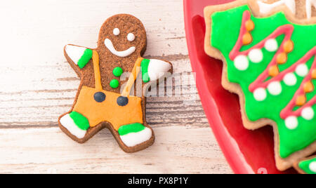 Lecker und süß gebackenen Weihnachtsplätzchen (Lebkuchen) mit schönen Weihnachten Dekoration in Rot Platte auf Licht Holztisch, Hintergrund, Nahaufnahme, Kopieren spac Stockfoto