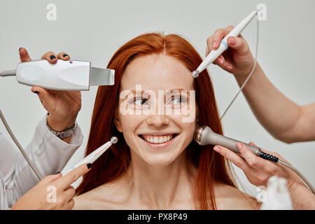 Konzeptionelle Bild der weiblichen emotionale Gesicht und kosmetologe Hände mit Geräten Stockfoto
