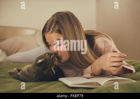 Schöne Frau mit Buch und Zeit mit ihrer Katze. Stockfoto