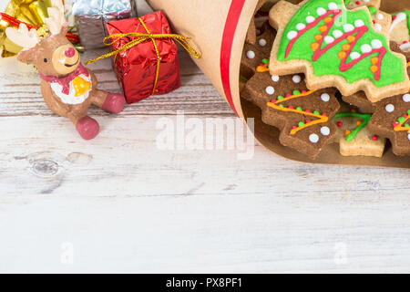 Lecker und süß gebackenen Weihnachtsplätzchen (Lebkuchen) mit schönen Weihnachten Dekoration in Papiertüte auf hellem Holztisch, Hintergrund, Nahaufnahme, Kopieren spac Stockfoto