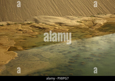 Teich mit sichtbaren Boden, Steine im Wasser und Haufen von Sand mit einer sehr interessanten Textur, in der Ausgrabung der Alten gravelyard. Schließen, horiz. Stockfoto