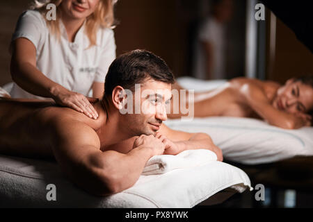 Junge Paare, die eine Rückenmassage in einem Spa Center Stockfoto