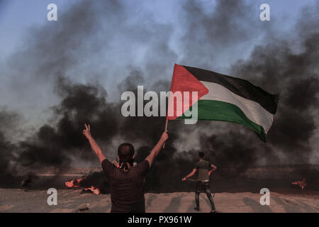 Gaza, Palästina. 24 Sep, 2018. Eine palästinensische Demonstrator wirft die Flagge von Palästina und Zeichen der Sieg mit seinem Finger während eines Protestes mit israelischen Truppen während einer Demonstration für die Aufhebung der israelischen Belagerung von Gaza und fordern das Recht auf Rückkehr in ihre Heimat auf den Grenzzaun zwischen Israel und Gaza im südlichen Gazastreifen. Credit: Yousef Masoud/SOPA Images/ZUMA Draht/Alamy leben Nachrichten Stockfoto