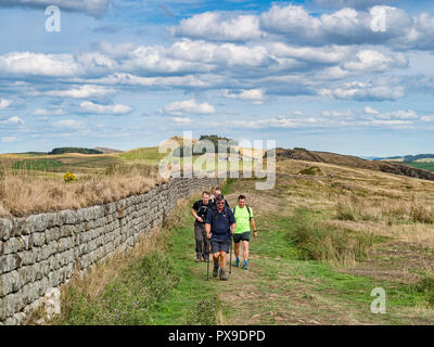 11. August 2018: Hadrian's Wall, Northumberland - Gruppe männlicher Wanderer mit Walking Stöcke walking auf den Hadrians Wall Path' an walltown Felsen auf einen Krieg Stockfoto