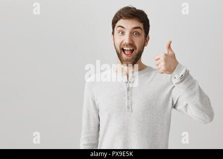 Ihre Idee ist genial. Indoor Portrait von aufgeregt und erfreut, Mann mit Daumen nach oben und zum Ausdruck bringen positive Stimmung Anhörung hervorragende Planung und Vereinbarung es zusammen mit Kollegen zu erfüllen Stockfoto