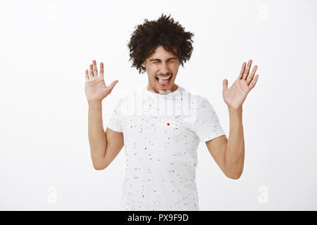 Lassen Sie uns die ganze Nacht durchfeiern. Gut aussehende sorglos und aufgeregt reife Hispanic Mann mit Schnurrbart und Afro Frisur die Handflächen hoch und schreiend aus Freude beim Tanzen und Spaß haben Stockfoto