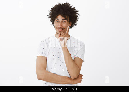 Sie erhielten. Portrait von zufrieden und charmante glückliche junge Mann mit Schnurrbart in ungezwungener weisses T-Shirt, der Zeigefinger und freudig lächelnd stimmt zwar mit Freund während eines Gesprächs Stockfoto