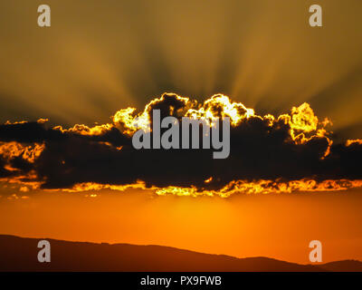 Untergehende Sonne hinter Wolken Stockfoto