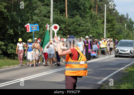 Eine junge Frau leitet den Straßenverkehr während der Wallfahrt zum Kloster von Jasna Gora in Czestochowa, Polen für das jährliche Fest der Himmelfahrt Mariens. Stockfoto