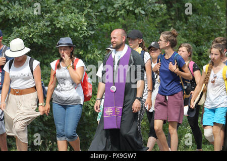 Ein katholischer Priester und andere Pilger zu Fuß auf der Straße während der Wallfahrt zum Kloster von Jasna Gora in Czestochowa, Polen. Stockfoto