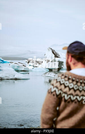 Eine isländische Reiseführer Tragen eines traditionellen Lopapeysa Isländische wolle Pullover Am Gletschersee Jökulsárlón Gletscherlagune in Island. Schwerpunkt der Version Stockfoto