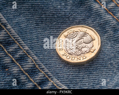 Neue Pound Münze und Hosentasche. Metapher für "das Pfund in der Tasche' oder Tasche änderung, UK Löhne Konzept, Pfund Sterling, letzten Pfund in der Tasche. Stockfoto