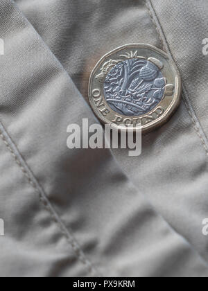 Neue Pound Münze und Hosentasche. Metapher für "das Pfund in der Tasche' oder Tasche änderung, UK Löhne Konzept, Pfund Sterling, letzten Pfund in der Tasche. Stockfoto