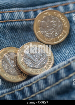 Neue Pound Münze und Hosentasche. Metapher für "das Pfund in der Tasche' oder Tasche änderung, UK Löhne Konzept, Pfund Sterling, letzten Pfund in der Tasche. Stockfoto