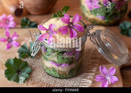 Vorbereitung der Kräuter Sirup gegen Husten von wilden gemeinsamen Malve Blumen, Blätter und Rohrzucker Stockfoto