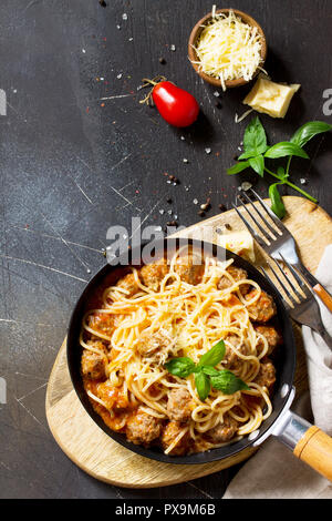 Spaghetti mit Hackbällchen mit Tomatensauce und Parmesan Käse auf einem dunklen Stein oder Beton Hintergrund. Ansicht von oben flach Hintergrund. Kopieren Sie Platz. Stockfoto
