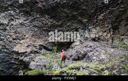 Mann, der vor basaltsäulen Wand in Gjain Canyon, Island. Stockfoto