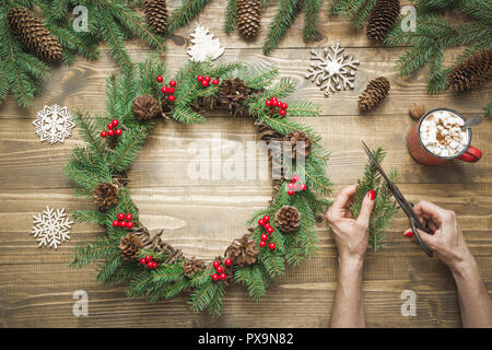 Frau, die Weihnachten Kranz mit frischen natürlichen Materialien. Weihnachten. Werkstatt. Stockfoto