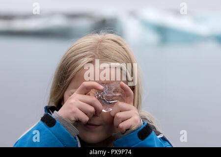 Junge Mädchen suchen durch klare Gletschereis aus dem Breidamerkurjokull Gletscher Gletscherlagune Jokulsarlon, Island. Stockfoto