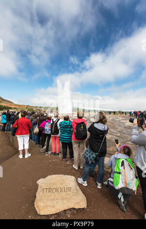 Touristen beobachten der Eruption des Strokkur Geysir, Haukadalur Tal, Fluss Hvítá, Island. Stockfoto