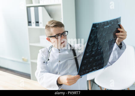 Junge kaukasier Arzt sitzt in seinem Büro und suchen X-ray Image Stockfoto