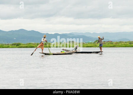 Reisen: Lokale junge Burmesische fischer Tragen von Manchester United Shirt, Lastausgleich und Lenkung Boot mit seinem Fuß in Inle See, Burma, Myanmar, Asien Stockfoto