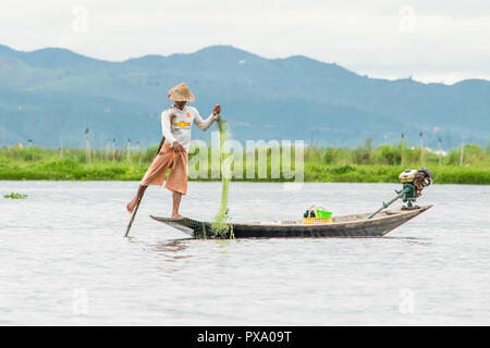 Reisen: Lokale junge Burmesische fischer Tragen von Manchester United Shirt, Lastausgleich und Lenkung Boot mit seinem Fuß in Inle See, Burma, Myanmar, Asien Stockfoto