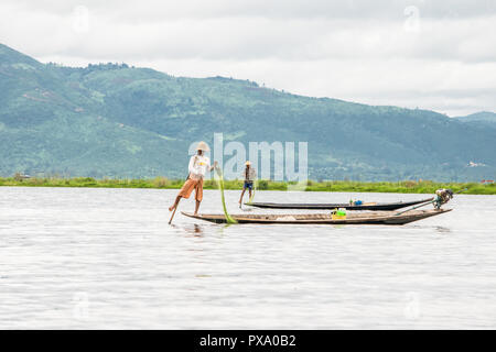 Reisen: Lokale junge Burmesische fischer Tragen von Manchester United Shirt, Lastausgleich und Lenkung Boot mit seinem Fuß in Inle See, Burma, Myanmar, Asien Stockfoto