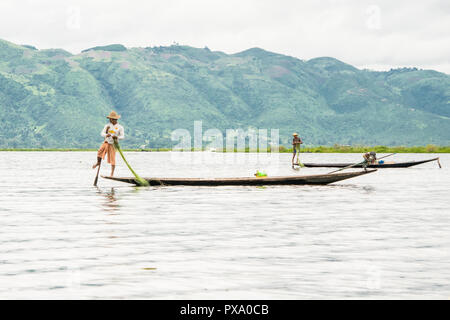 Reisen: Lokale junge Burmesische fischer Tragen von Manchester United Shirt, Lastausgleich und Lenkung Boot mit seinem Fuß in Inle See, Burma, Myanmar, Asien Stockfoto