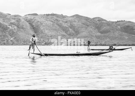 Reisen: Lokale junge Burmesische fischer Tragen von Manchester United Shirt, Lastausgleich und Lenkung Boot mit seinem Fuß in Inle See, Burma, Myanmar, Asien Stockfoto