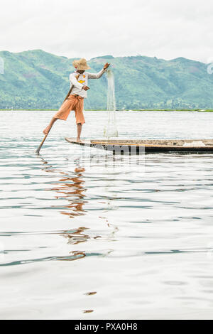 Reisen: Lokale junge Burmesische fischer Tragen von Manchester United Shirt, Lastausgleich und Lenkung Boot mit seinem Fuß in Inle See, Burma, Myanmar, Asien Stockfoto