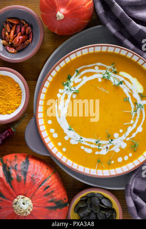 Kürbis creme Suppe in Keramik Schüssel gewürzt mit Sahne und Kresse Keimsprossen auf hölzernen Hintergrund Stockfoto