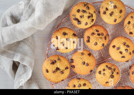 Zwölf frisch gebackene choco Chip muffins Abkühlen auf Drahtgeflecht auf Holz mit Bettwäsche Handtuch, Flachbild Layout Stockfoto