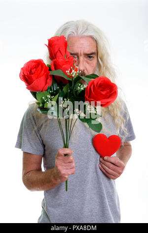 Studio shot der älteren bärtigen Mann versteckt sich hinter roten Rosen während Stockfoto