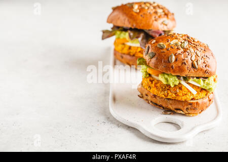 Vegane Kartoffel (oder Kürbis) Burger auf weißen Hintergrund. Pflanzlichen Burger, Avocado, Gemüse und Brötchen. Sauber Essen, pflanzliche Nahrung Konzept. Stockfoto