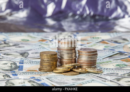 Stapel von Münzen auf die verstreuten Notizen von einhundert Dollar. Stockfoto