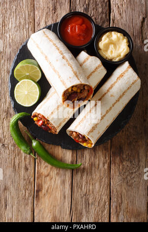 Mexikanische beliebte Gegrillte burrito Snack mit Rindfleisch und Gemüse und mit Soßen close-up auf den Tisch. Vertikal oben Ansicht von oben Stockfoto